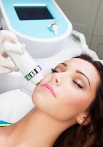 Woman getting laser face treatment in medical spa center